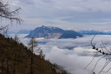 Scenic view from mountain peak Schwarzkogel to Dobratsch in Karawanks mountains in Carinthia, Austria. Magical atmosphere in remote landscape in Slovenian Austrian Alps. Misty fog and clouds in valley