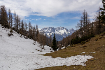 Snow covered alpine meadows with scenic view of snow capped mountain range of Julian Alps. Hiking...