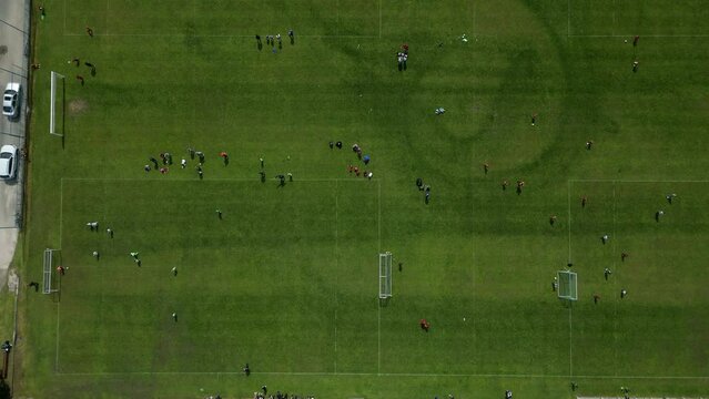 sports stadium forball match with several goals. the children here have a series of elimination school grade matches. observe the swarm vertically downwards. mowed stripes lawn