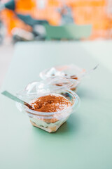 Traditional Italian Classic sweet tiramisu dessert in plastic packaging plate on table in a cafe. High quality photo