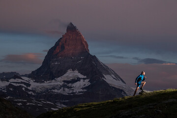 Alpine trail running at dusk with mountain backdrop