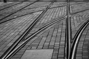 Complex network of tram tracks crisscrossing on cobblestone streets in black and white, Rotterdam