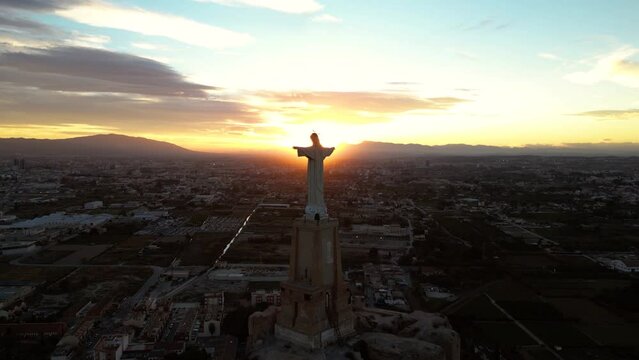 Christ of Monteagudo, Murcia, Spain. Drone aerial view at sunset in silhouette against the light. The sunlight back lights his chest.