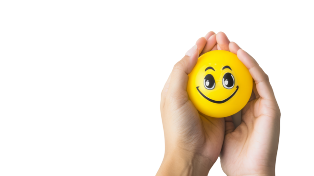 Hand holding a smiley face stress ball against a transparent background, conveying positivity and stress relief.