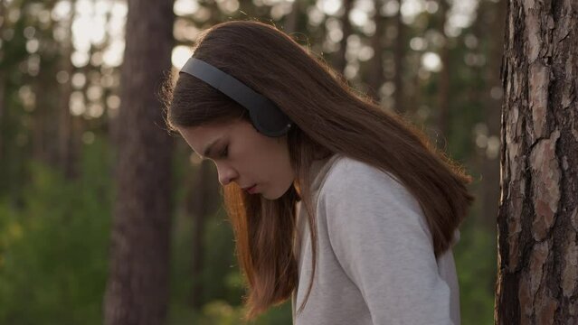Pensive lady with headphones in forest
