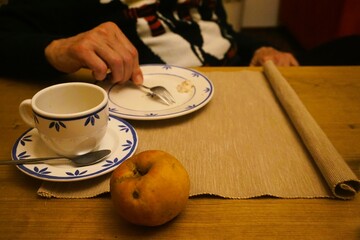 Gedeckte Kaffeetafel mit gelbem Apfel auf Tisch, brauner Stoffunterlage, blau-weiß gemustertem...