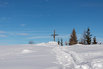 Obraz premium Panoramic hiking trail trough deep snow leading to the mountain summit of Matschacher Gupf in Karawanks, Carinthia, Austria. Snow capped mountain peak of Austrian Alps. Snow shoe and ski tour prints