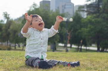 White boy with down syndrome sitting on the grass playing in a park