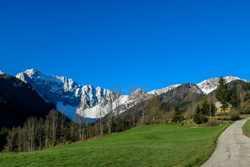 Panoramic hiking trail along lush green alpine meadows and forest with scenic view of Karawanks mountain range in Carinthia, Austria. Remote villages on alpine landscape in Bodental, Austrian Alps