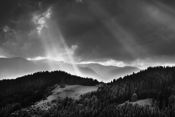 Amazing landscape of mountains hills in sunbeam and cloudy sky in black and white shadow light. Monochrome style.
