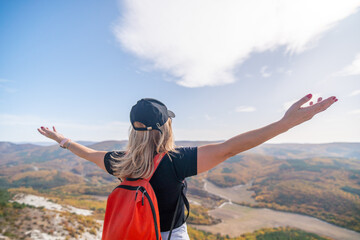 woman backpack on mountain peak looking in beautiful mountain valley in autumn. Landscape with sporty young woman, blu sky in fall. Hiking. Nature