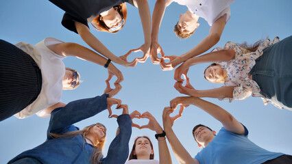 Young friends stand in a circle and make hearts out of their hand wrists.