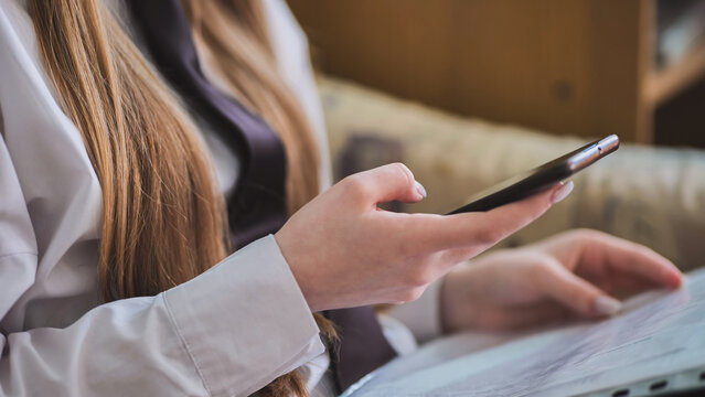 A girl's hands with a smartphone in close-up.