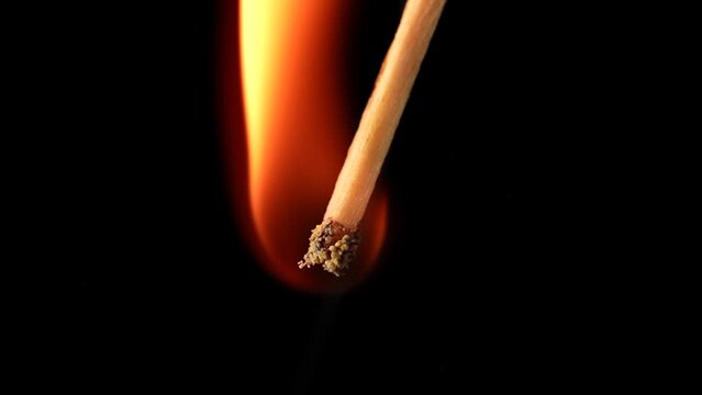 Macro video captures the moment of ignition of the match and its flame. From the flare up to the bright burning. The red sulfur of the match flashes fire and the wood burns. Symbolizing energy.