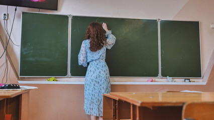 A girl student writes on the green board.