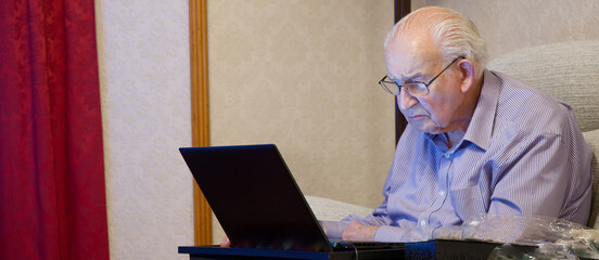 Old elderly senior man using a laptop computer at risk to cyber attack and online bank fraud