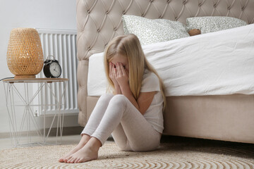 Little girl sitting in the bedroom, crying and covering face with hands - Powered by Adobe