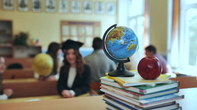 Globe of the world with textbooks and an apple in the background of a lesson in a school classroom.