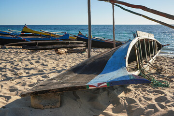 Simple wooden fishing boats on a sandy beach near small Madagascar village, calm sea in background