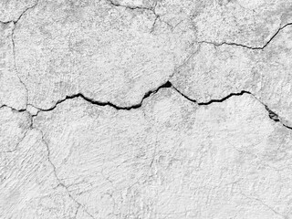 The wall of an old building with crumbling plaster and many winding, deep cracks. Copy space. Black and white photo. Selective focus.