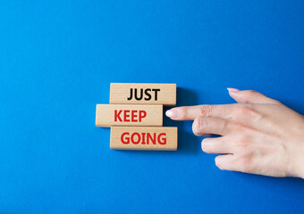 Just keep going symbol. Concept words Just keep going on wooden blocks. Beautiful blue background. Businessman hand. Business and Just keep going concept. Copy space.