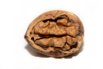 Close-up of a single walnut against a white background. The nut is partially open. You can see the contents.