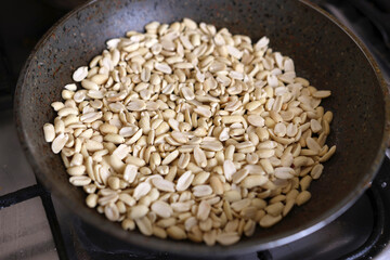 Raw peanuts are fried in a pan