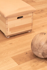 Medizinball aus Leder und kleiner Kasten auf einem Holzboden