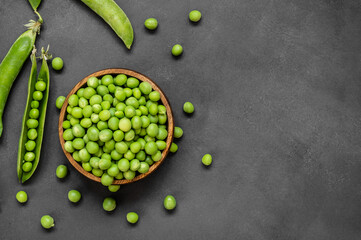 Fresh green peas with pod in wooden bowl on rustic background, healthy green vegetable or legume ( pisum sativum ) - obrazy, fototapety, plakaty
