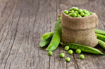 Fresh green peas with pod in burlap sack on wooden  background, healthy green vegetable or legume ( pisum sativum ) - obrazy, fototapety, plakaty