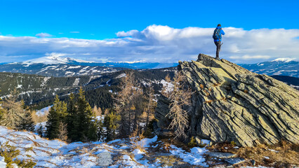 Man with backpack standing on massive rock formation at Steinerne Hochzeit, Saualpe, Lavanttal...
