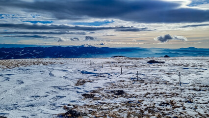 Snow covered alpine meadow with scenic view of Karawanks and Lavanttal Alps, Carinthia, Austria. Snow has irregular patterns resembling ground texture. Extreme terrain in the Austrian Alps in winter