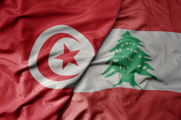 big waving national colorful flag of lebanon and national flag of tunisia .
