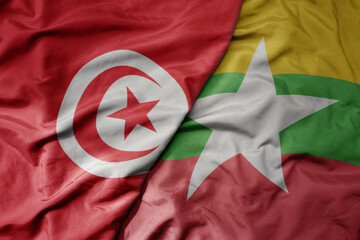 big waving national colorful flag of myanmar and national flag of tunisia .