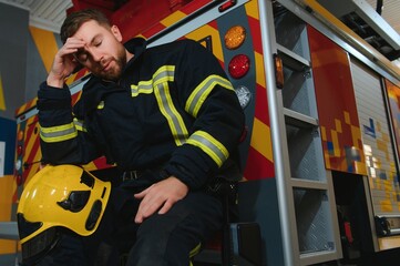 A seated and sweating firefighter is exhausted, distressed and tired after being overwhelmed in a...