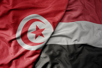 big waving national colorful flag of yemen and national flag of tunisia .