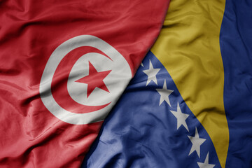 big waving national colorful flag of bosnia and herzegovina and national flag of tunisia .