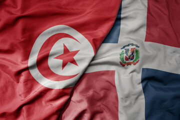 big waving national colorful flag of dominican republic and national flag of tunisia .