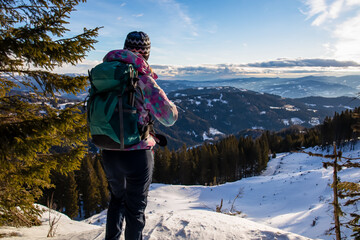 Backpack woman with scenic view of Lavant valley and Koralpe in Carinthia, Styria, Austria. Winter...