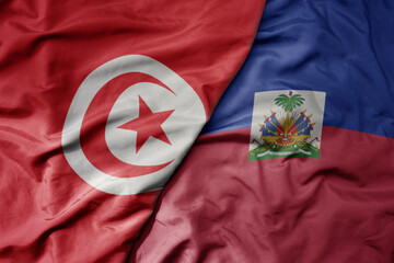 big waving national colorful flag of haiti and national flag of tunisia .