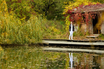 A young beautiful girl walks by the lake in an autumn park