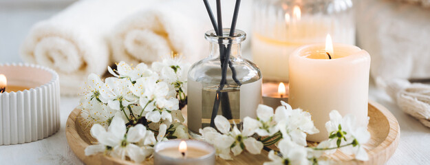 Concept of pure natural organic ingredients, flowers, herbal extracts in cosmetic beauty products. Perfumery, home fragrance with the scent of blooming spring flowers. Candles, bamboo tray. Banner