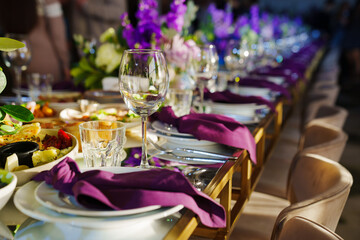 Beautiful festive table setting with flowers and purple napkins. 