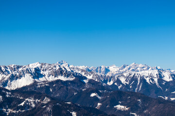Fototapeta na wymiar Scenic view on snow capped mountain peaks of Karawanks, Julian and Kamnik Savinja Alps in Carinthia (Kaernten), Austria. Winter wonderland in Austrian Alps, Europe. Aerial view from Ferlacher Horn