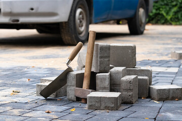 Hammer and trowel on the sidewalk with concrete bricks. - obrazy, fototapety, plakaty
