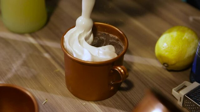 pouring whipped cream into cold drink in copper mug. moscow mule