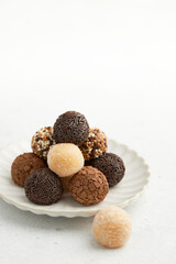 Typical Brazilian sweet brigadeiro. A heap of assorted flavors of candies on a white table 