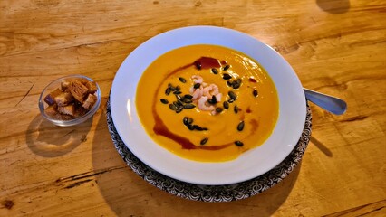 Pumpkin soup in large white bowl prepared for lunch is delicious and healthy