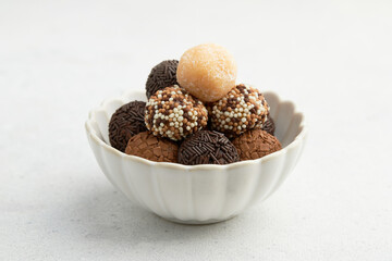 Typical Brazilian sweet brigadeiro. A heap of assorted flavors of candies on a white table