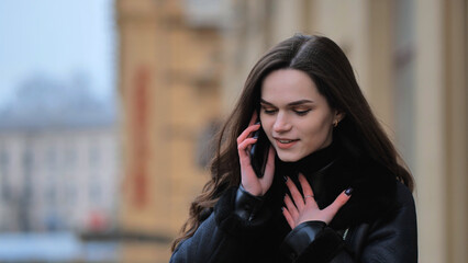 Beautiful stylish brunette girl talking on the phone on the street